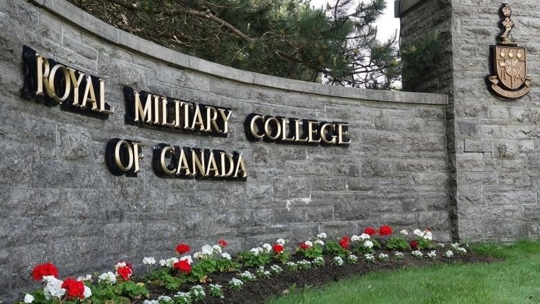 A brick wall with the words "Royal Military College of Canada" in gold letters, with red and white flowers in a bed running in front of it.