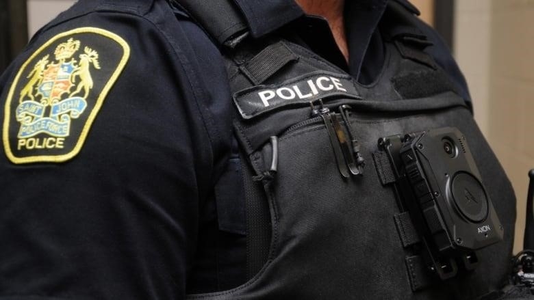 Closeup of male officers' upper chest, wearing a vest with a small black camera affixed to the vest.