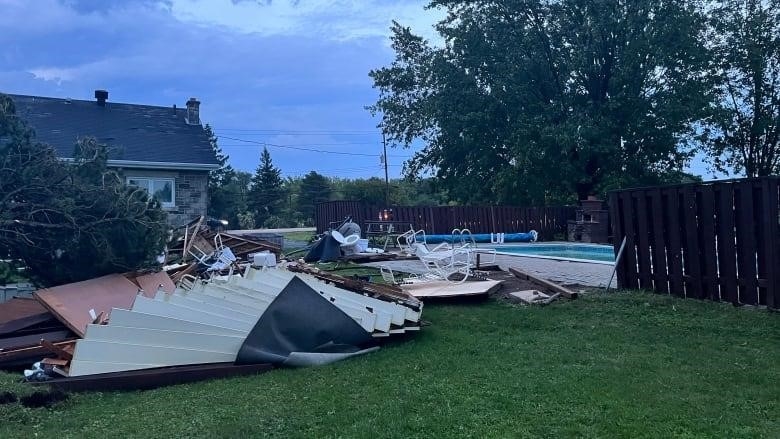 Trees and debris spread across the backyard of a family residence.