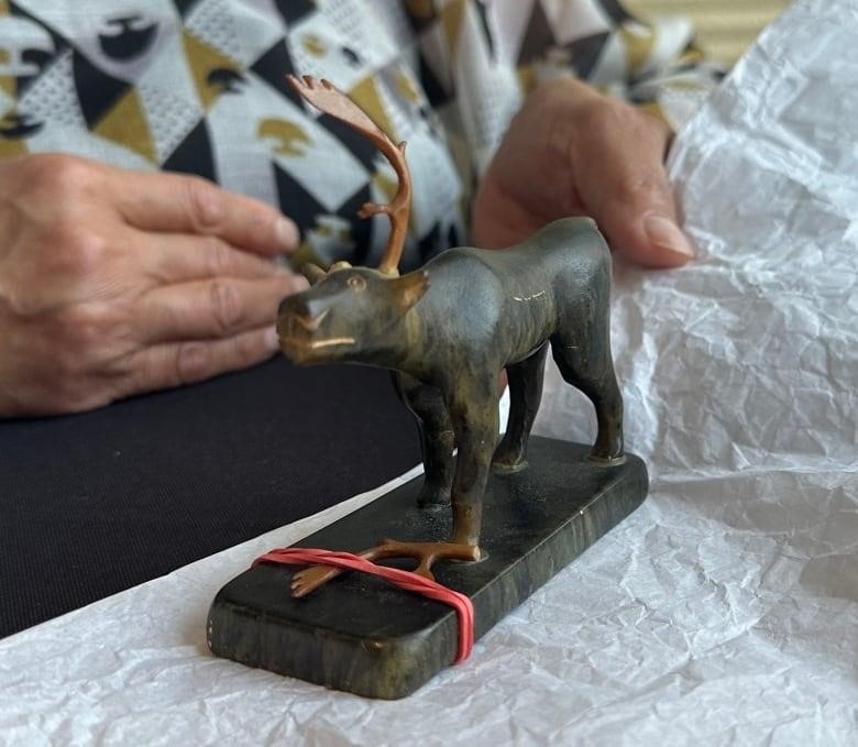 woman stands with small caribou statue