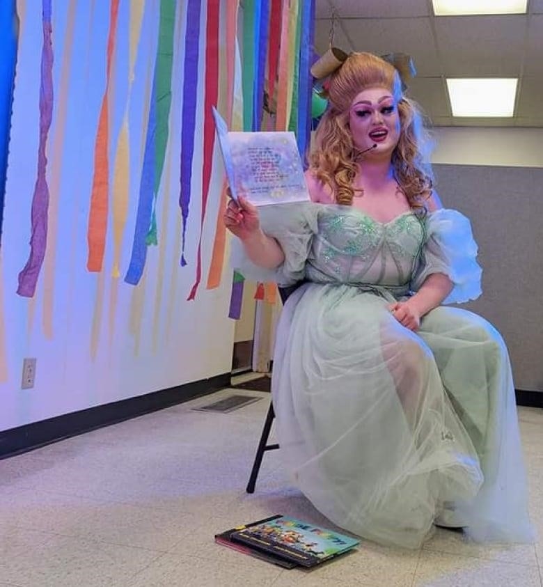 A drag queen wearing a gown reads a book at the Arnprior public library's drag storytime event.