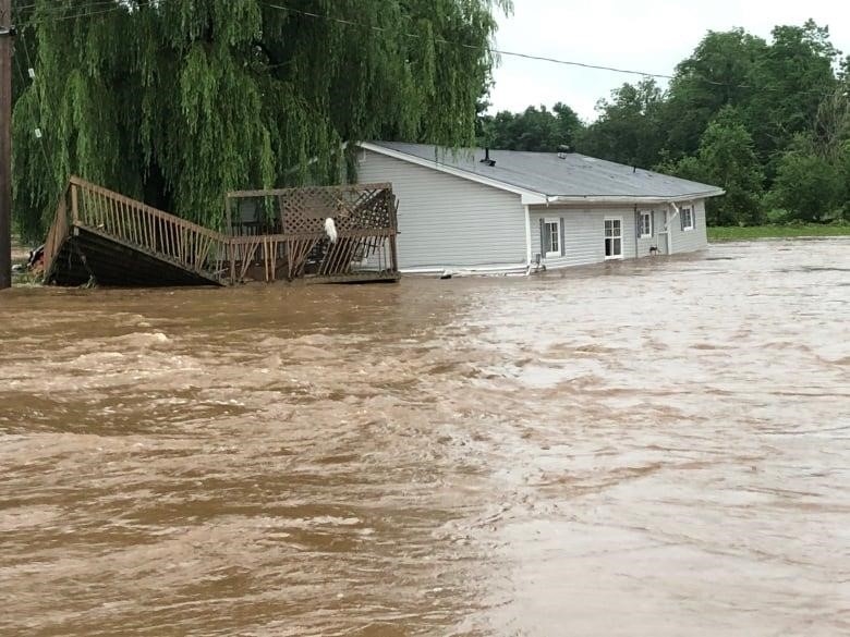 A house and separated deck are seen in the floodwaters of Windsor, N.S.